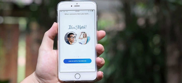 Photo of someone holding up their cell phone with a Tinder screenshot
