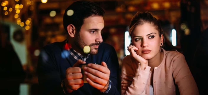 Photo of a woman looking worried in a restaurant with a man sitting next to her and looking at her Photo of a woman looking worried in a restaurant with a man sitting next to her and looking at her