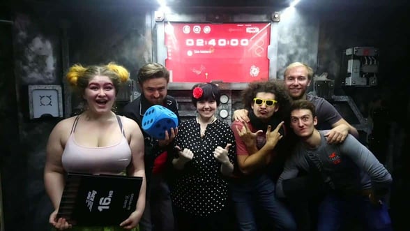 Photo of clueQuest staff in front of an escape room Photo of clueQuest staff in front of an escape room