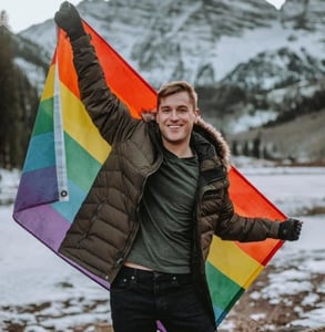 Photo of Mikah with a rainbow flag Photo of Mikah with a rainbow flag