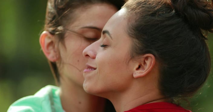 
LGBT lesbian couple flirting and cuddling outdoors. Young millennial gay female couple