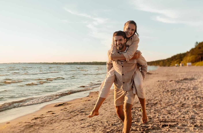 leisure and people concept - happy couple having fun on summer beach