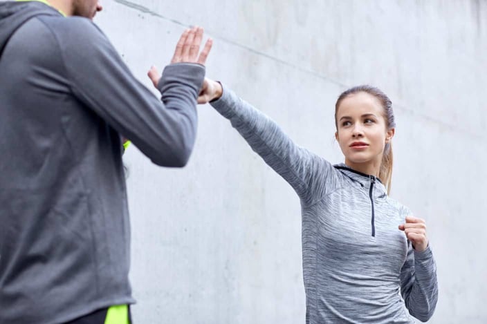 fitness, sport, martial arts, self-defense and people concept - woman with personal trainer working out strike outdoors