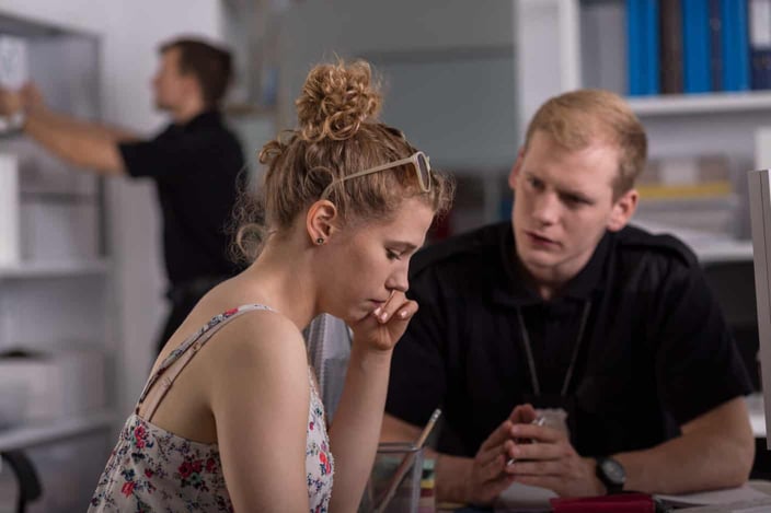 Shot of a sad young woman sitting at a police station with a young policeman Shot of a sad young woman sitting at a police station with a young policeman