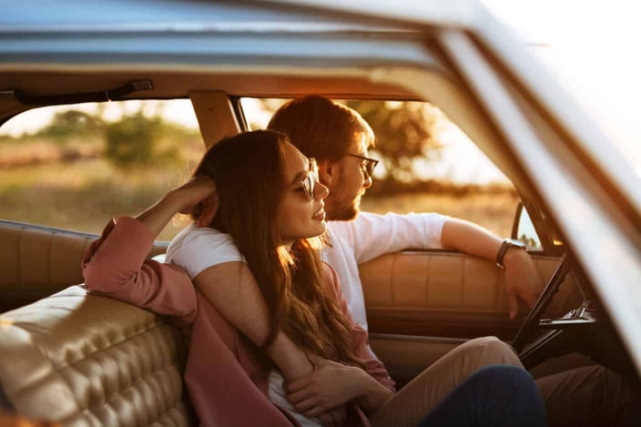 Young beautiful couple relaxing together while sitting inside a retro car Young beautiful couple relaxing together while sitting inside a retro car