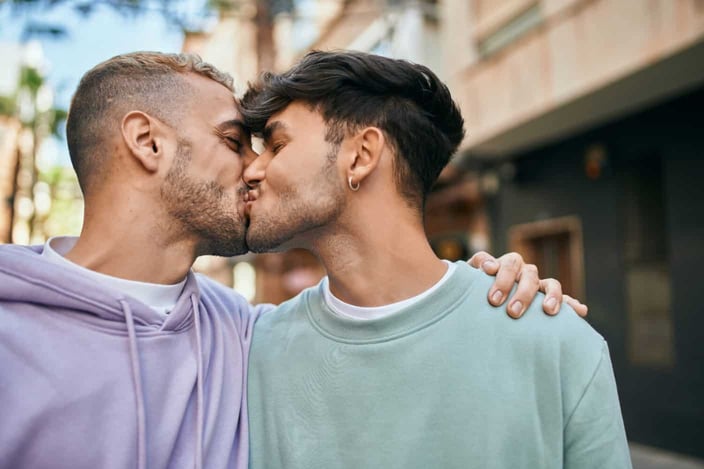 Photo of a young gay couple hugging and kissing at the city. Photo of a young gay couple hugging and kissing at the city.