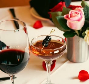 wine and cocktail on a table with rose petals