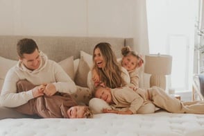 family smiling on bed