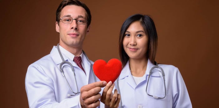 Two doctors holding a heart symbol