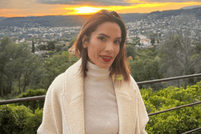 Woman standing outside in front of sunset smiling Woman standing outside in front of sunset smiling