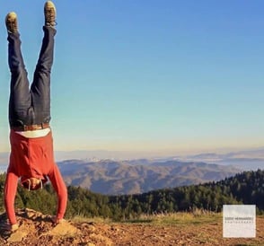 man doing handstand on cliff