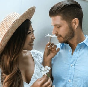 woman holds us flower to man so he can smell it