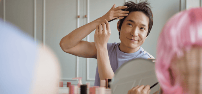 Non-binary Asian person styles their short hair Non-binary Asian person styles their short hair