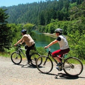 couple riding bikes through mountains couple riding bikes through mountains