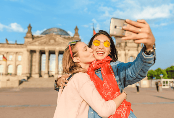 Two queer women taking a selfie in front of historic monument