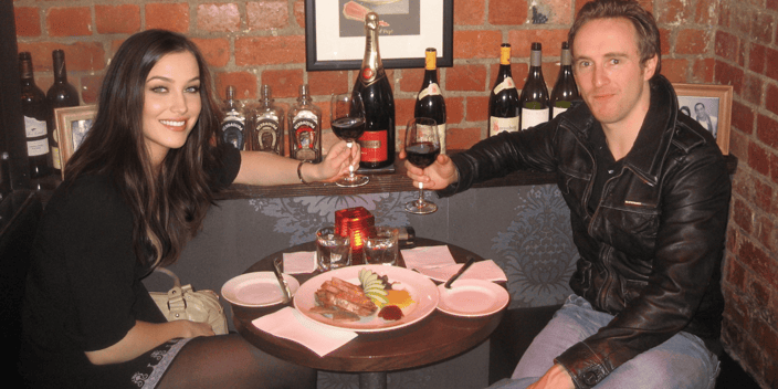 Dan Bacon and a former girlfriend clinking glasses of wine at a dinner table