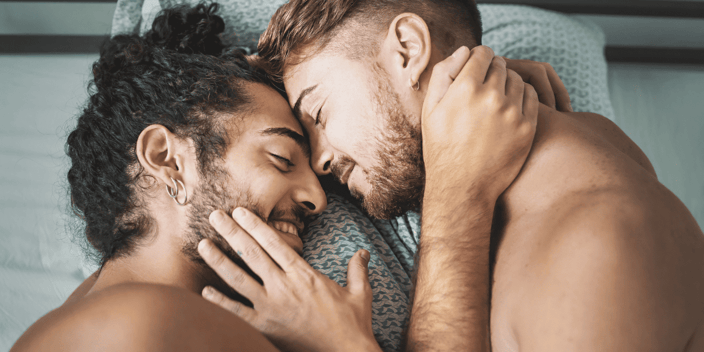 Gay couple holding each other close in bed