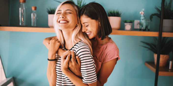 Lesbian couple holding each other in kitchen and smiling
