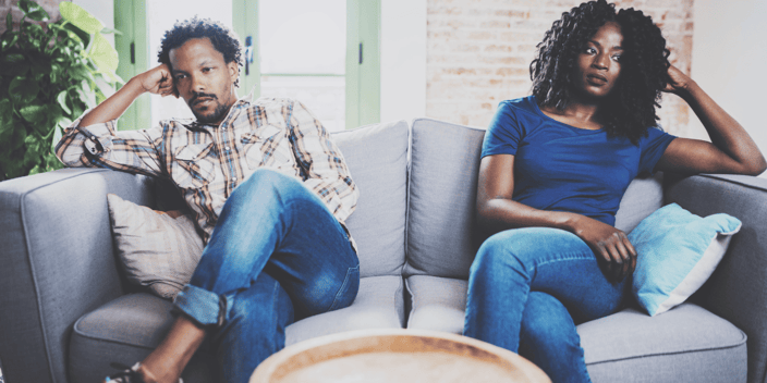 Black man and woman couple sitting apart upset on couch
