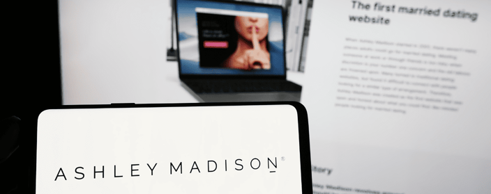 Ashley Madison logo in front of laptop with Ashley Madison website on screen