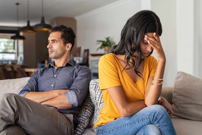 Middle eastern couple sitting on couch facing away from each other in conflict Middle eastern couple sitting on couch facing away from each other in conflict