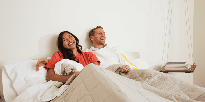 Couple laughing in bed sitting under Slumber Cloud comforter