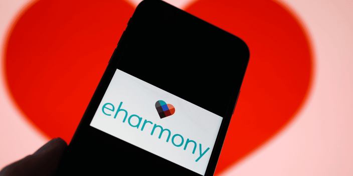 eharmony logo on a cellphone in front of a big red heart