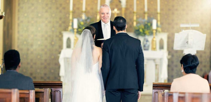 Bride and groom standing in front of a priest during a church wedding