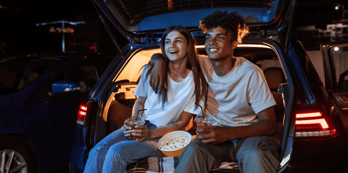 Young couple sitting in trunk of car watching movie Young couple sitting in trunk of car watching movie