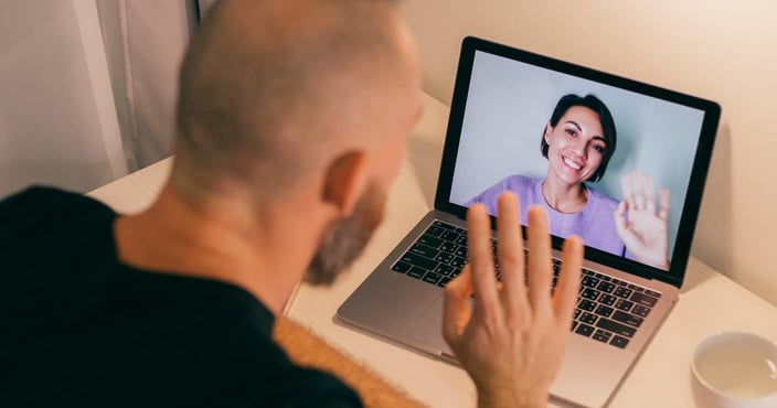 Man waves at woman over video call. Man waves at woman over video call.