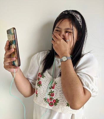 Woman holding phone hand over mouth Woman holding phone hand over mouth