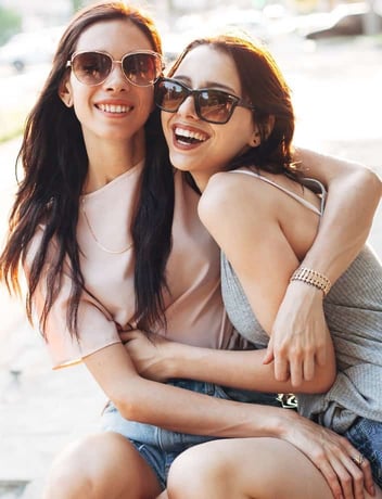 Women hugging wearing sunglasses Women hugging wearing sunglasses
