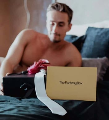 The Fantasy Box sign on bed shirtless man