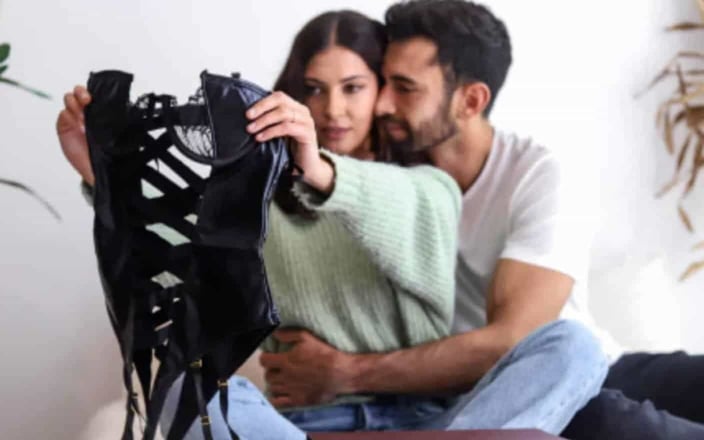 Man hugging woman holding lingerie