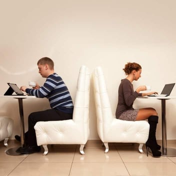 Man and woman using laptops back to back 
