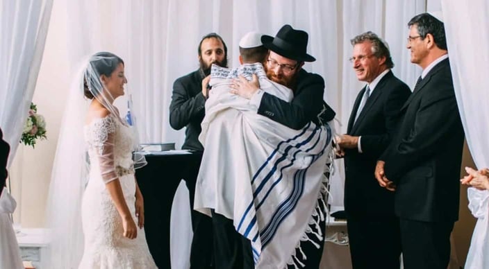 Rabbi Bernath as officiant at wedding, hugging the groom Rabbi Bernath as officiant at wedding, hugging the groom