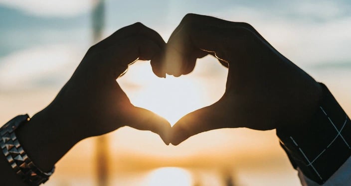 Hands making a heart at sunset