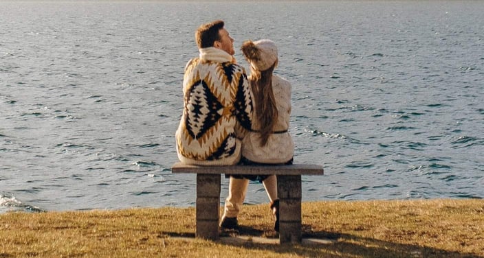 Inland Empire Couples Counseling couple wearing sweaters sitting on bench near lake 