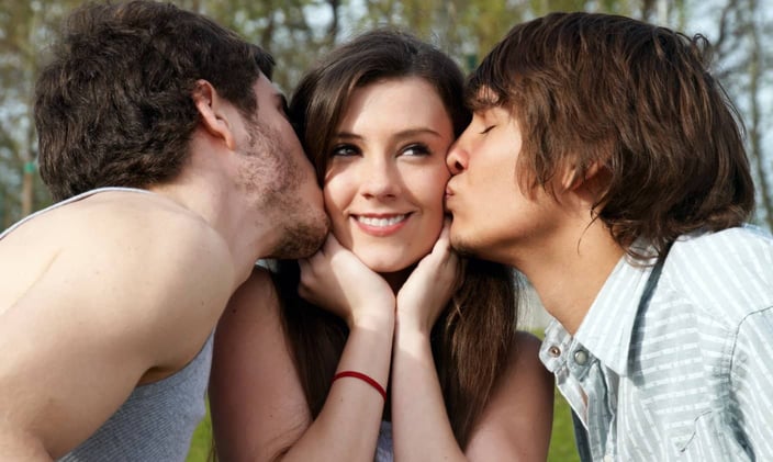 Two men kissing woman on the cheek