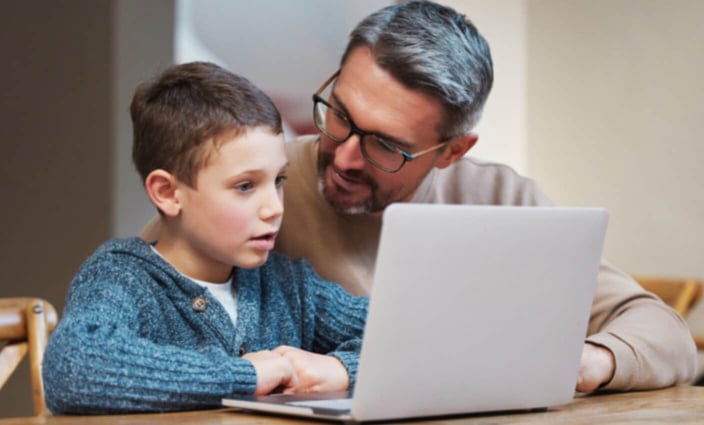Photo of a father and his young son using a laptop together
