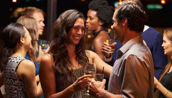 Photo of a man and a woman drinking wine and smiling at a party