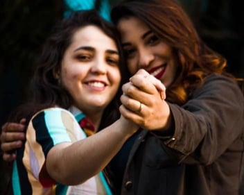 A photo of two women holding hands and smiling together