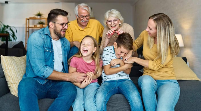 Grandparents, parents, and children laughing together on the couch