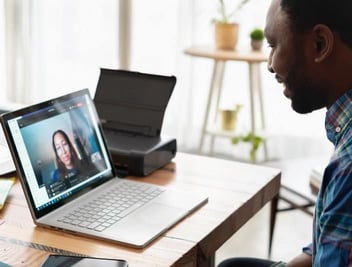 Photo of Black man smiling while doing telehealth appointment with a therapist 