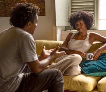 Photo of a young couple having a serious discussion on a yellow couch Photo of a young couple having a serious discussion on a yellow couch