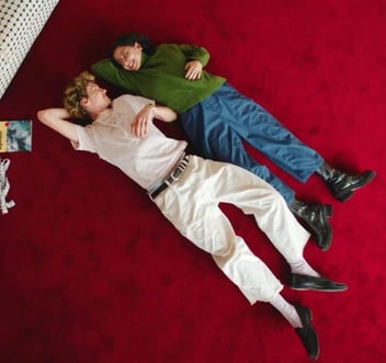 Screenshot from It's Funny We Met On Hinge commercial of a young couple lying on a red carpet and smiling at each other Screenshot from It's Funny We Met On Hinge commercial of a young couple lying on a red carpet and smiling at each other