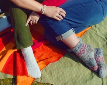 Screenshot from It's Funny We Met On Hinge commercial close up of a couple's legs and feet cuddling outside on a blanket Screenshot from It's Funny We Met On Hinge commercial close up of a couple's legs and feet cuddling outside on a blanket