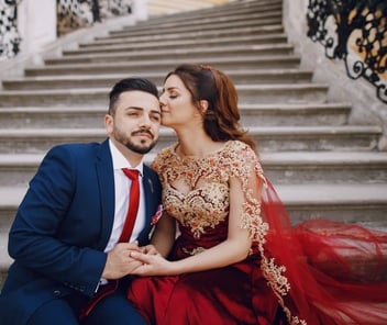 Photo of Indian woman kissing her male partner and holding hands on an outdoor staircase 