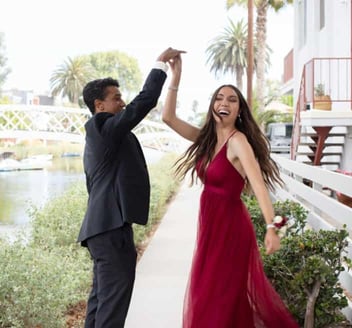 Photo of a young couple laughing and dancing together outdoors