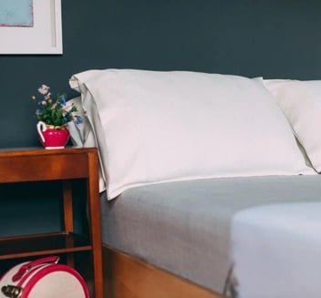 Photo of two white silk pillows on a bed with gray sheets Photo of two white silk pillows on a bed with gray sheets